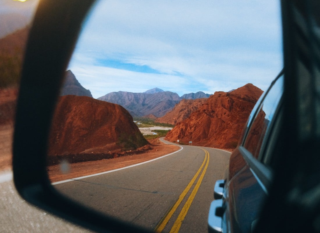 A car mirror is reflecting the red-coloured mountains in Cafayate. 