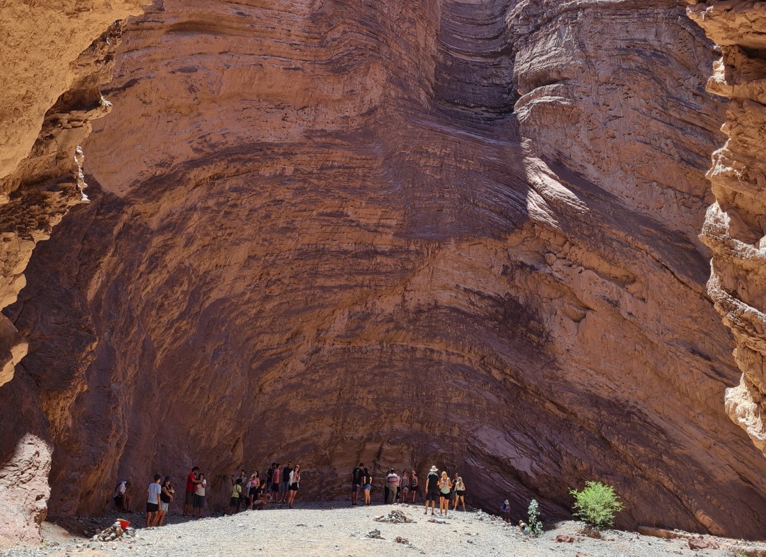 A group of people are standing in the middle of the red-brown-coloured Conchas Gorge in Argentina. 