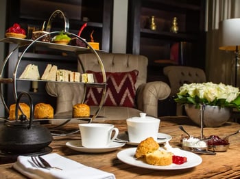 An afternoon tea is laid out inside one of the hotel's seating areas, offering scones, sandwiches, cakes and potted tea.