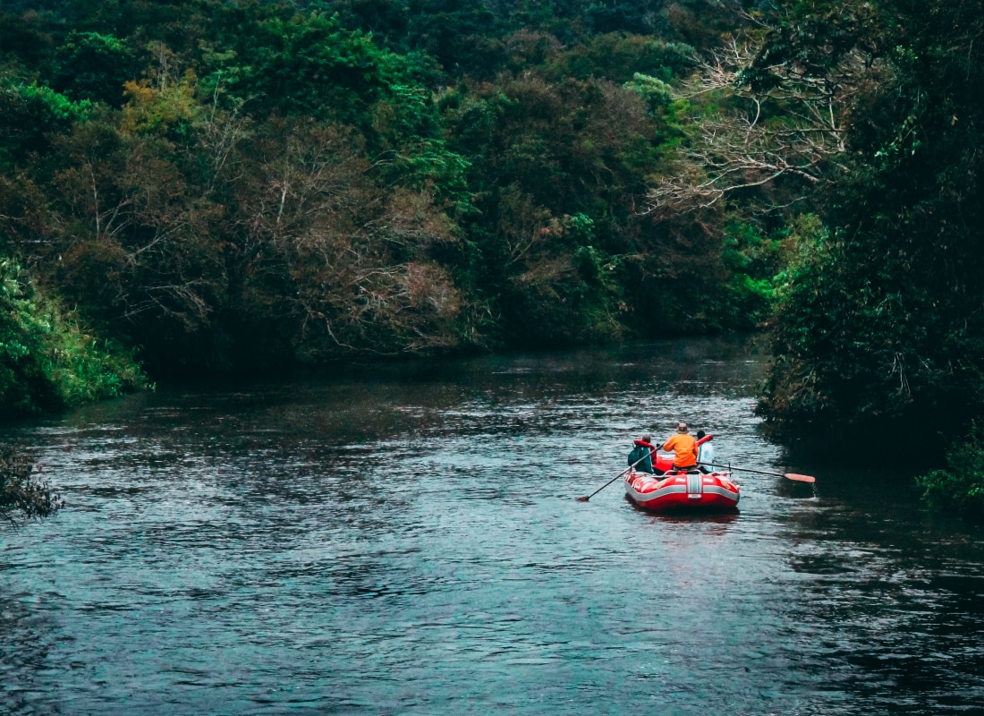 A red raft is cruising down a turquoise river. 