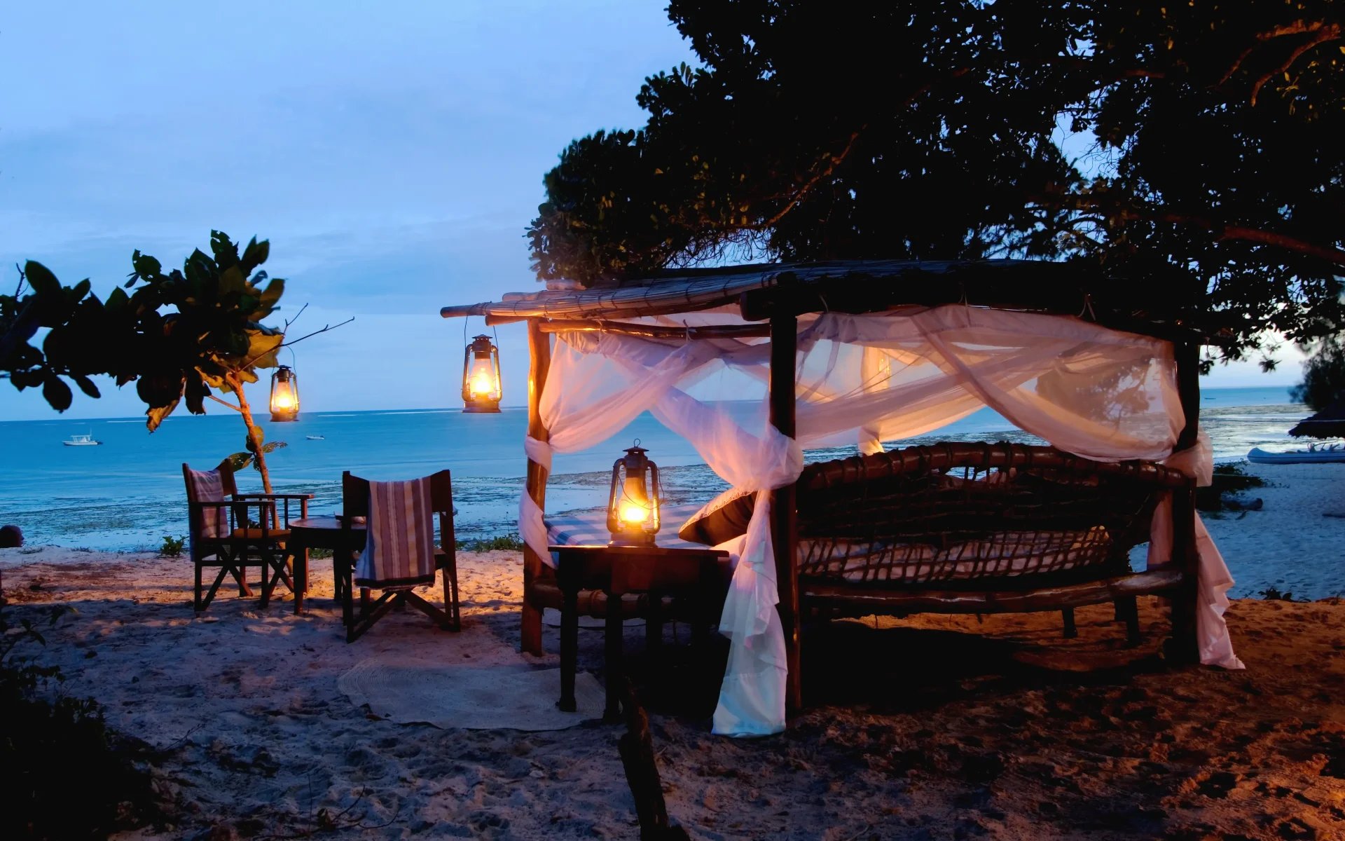 A cosy seating area is set up on the beach front at Kinondo Kwetu during the early evening. It is lit up by candlelight