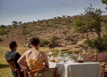A young couple enjoy private dining in the Borana bush as an elephant wanders past.