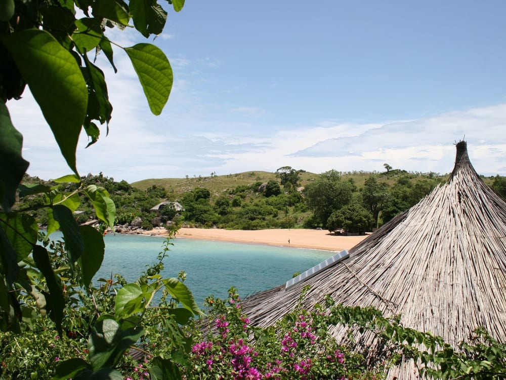 A glistening turquoise sea and beach with a thatch-roofed hut