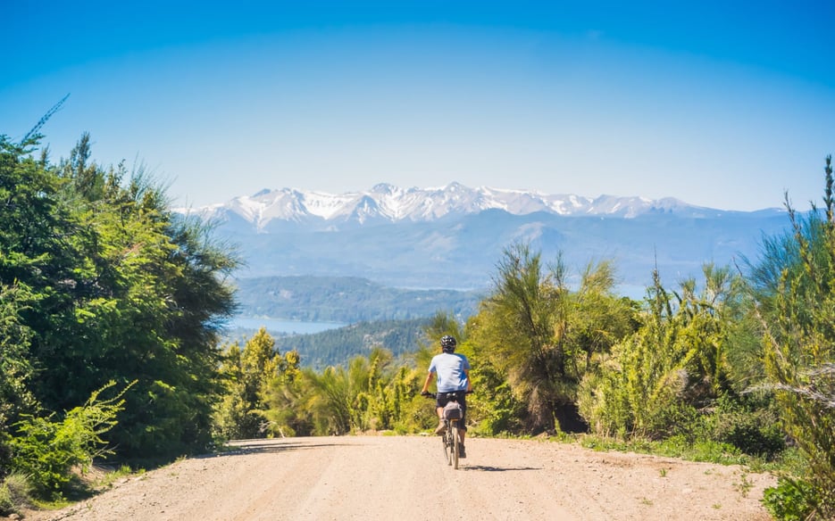 Man cycling towards mountain range