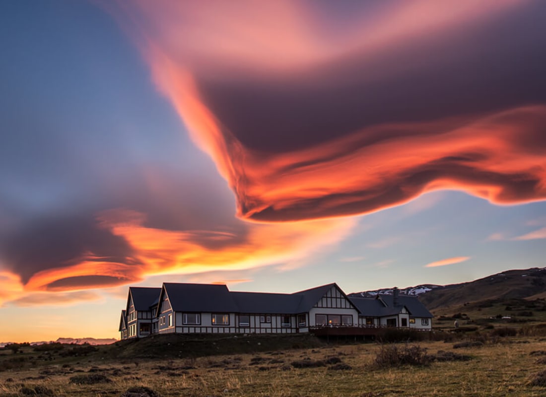 Eolo Lodge sits under a magnificent cloud and sunset of orange, blue and yellow. They look more like Northern Lights.
