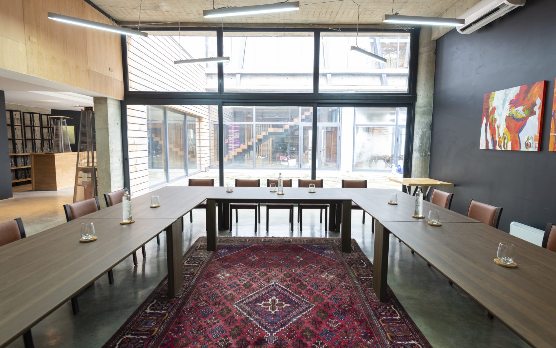 A horseshoe-shaped meeting table surrounds a bohemian rug and office space. 