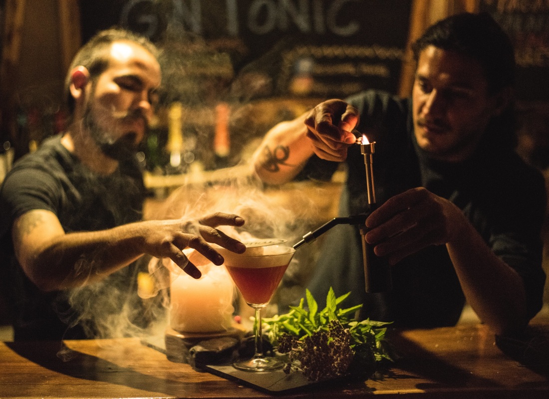 Two barmen are making a cocktail. 