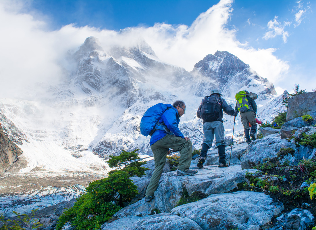 People are hiking to the French Valley in Patagonia over snowy mountains. 
