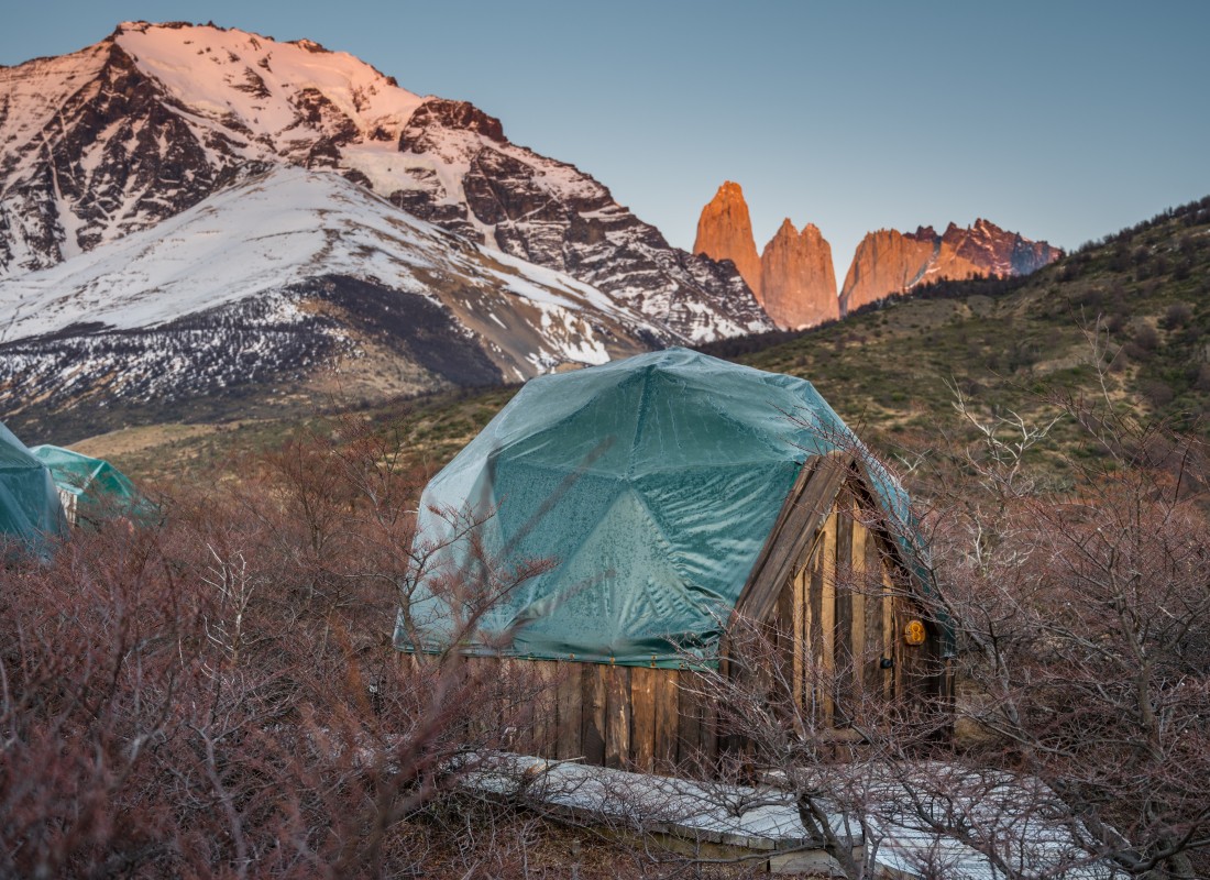 A dome sits in the trees with a snowy mountain in the background.