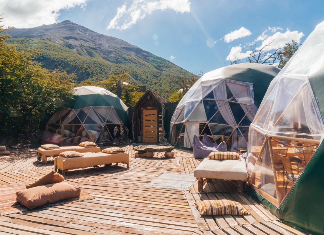 Three domes overlook a wooden deck with sofas and pillows. 
