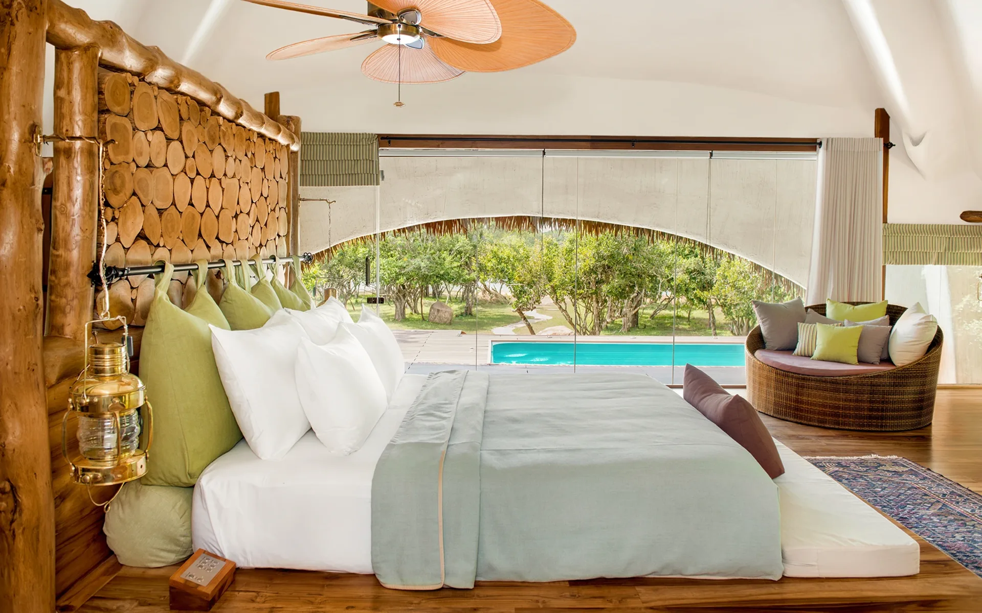A double bed surrounded by a chair and views of the pool.