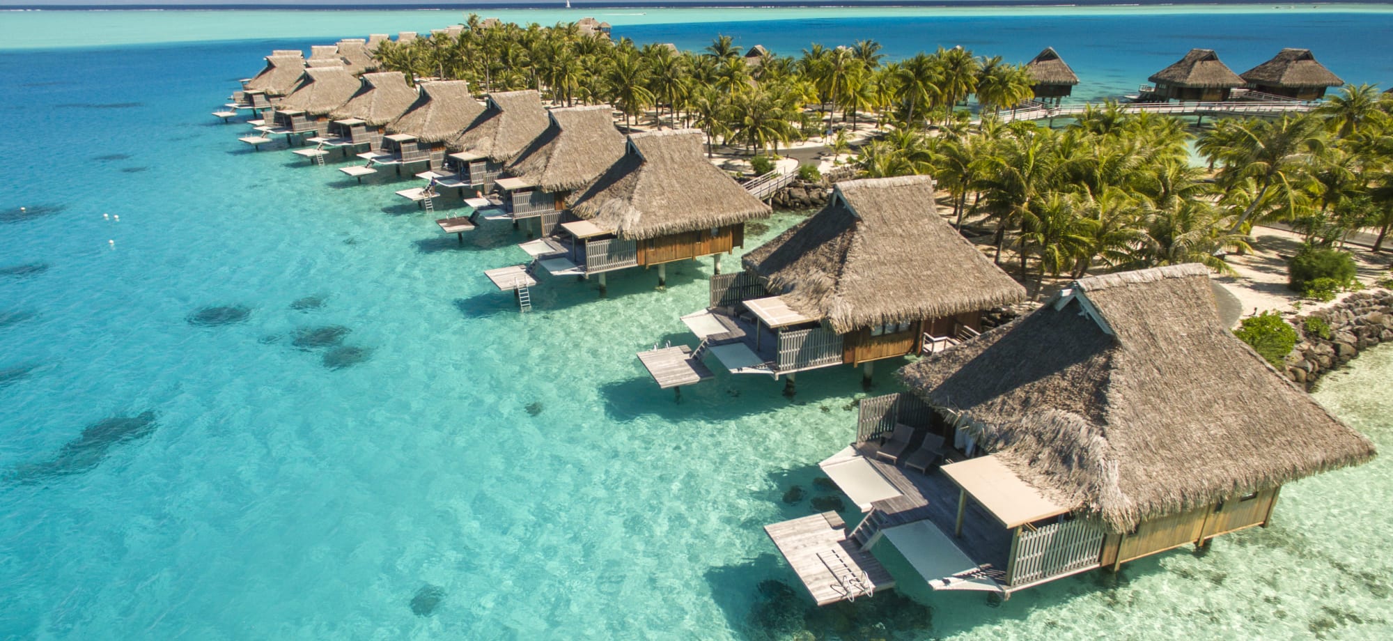 Overwater villas front a white sand and overlooking a private island. 