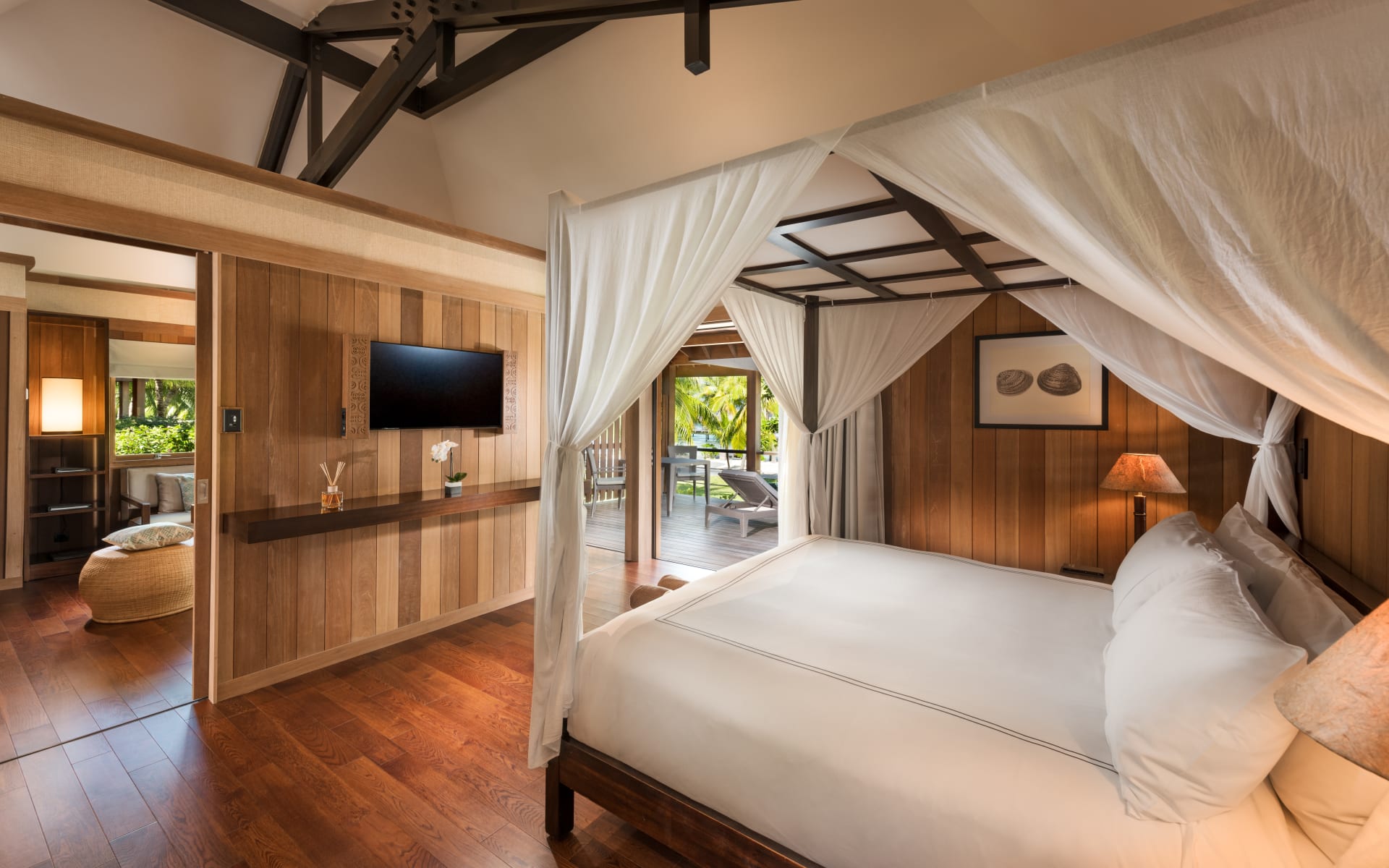 There is a white canopy bed in the middle of a wooden-designed room. 