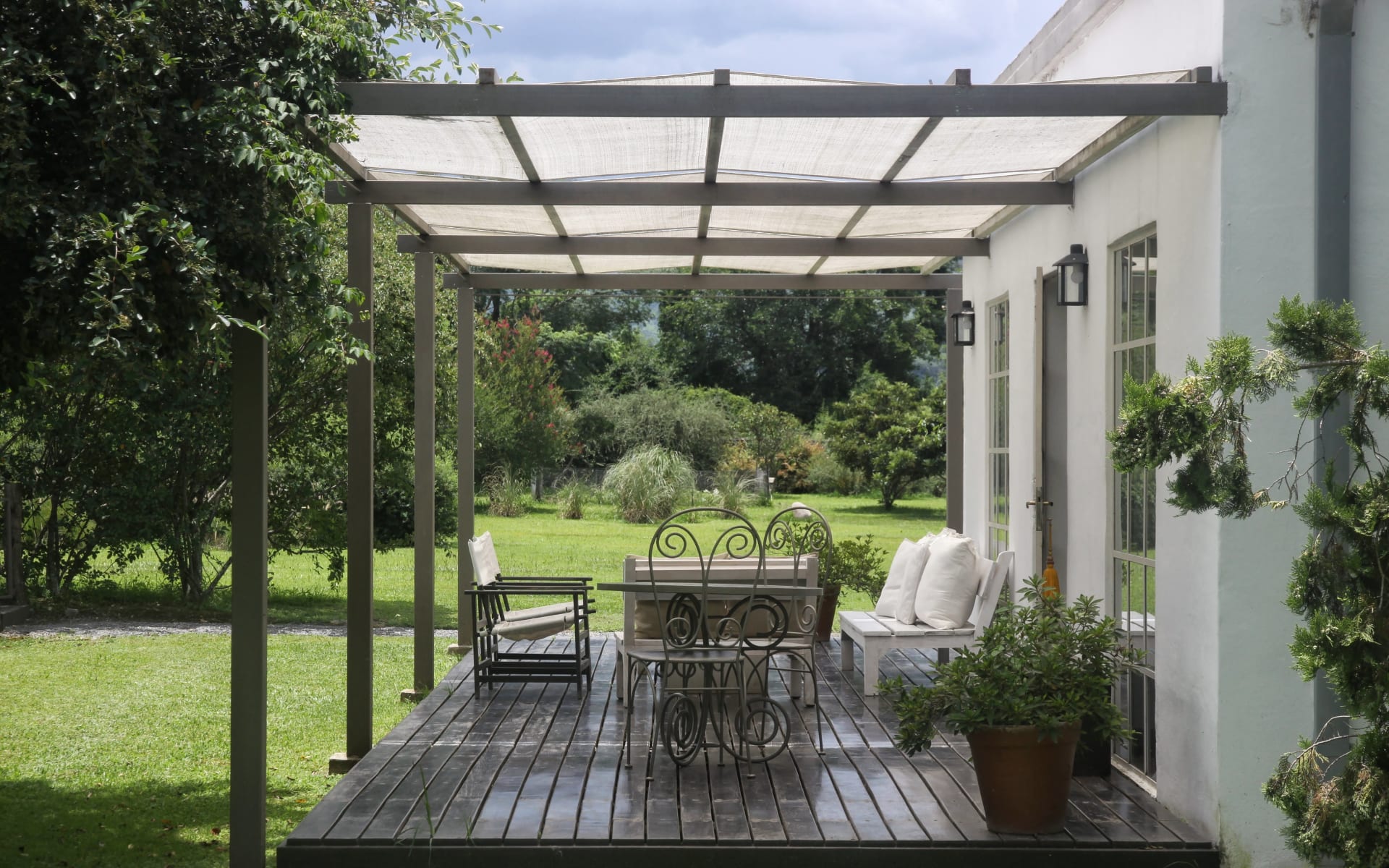 The veranda at Finca Valentina is covered with a white umbrella and has several sofas and chairs overlooking the garden. 