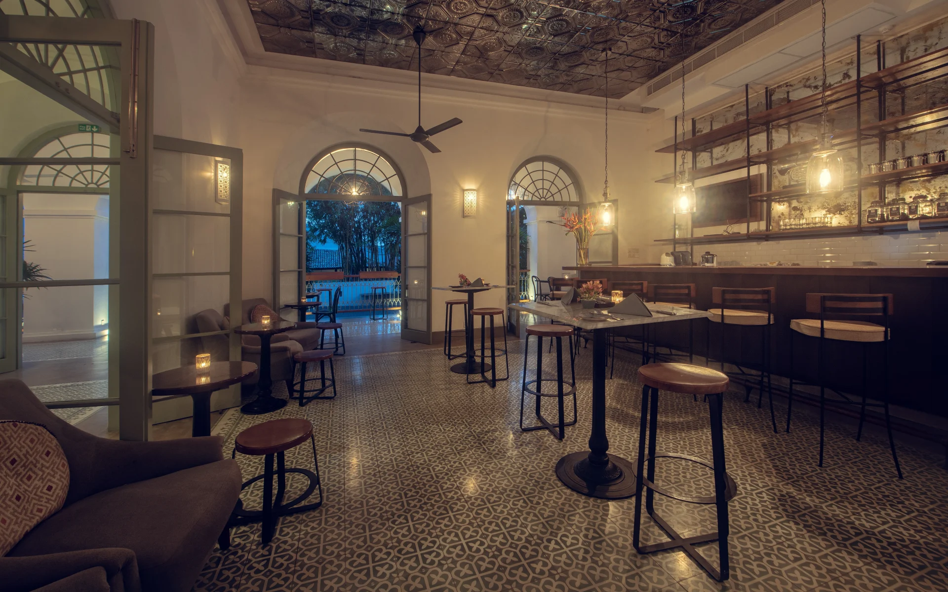 The bar at Fort Bazaar is dimly lit during an evening and its floor is tiled in a mosaic style.