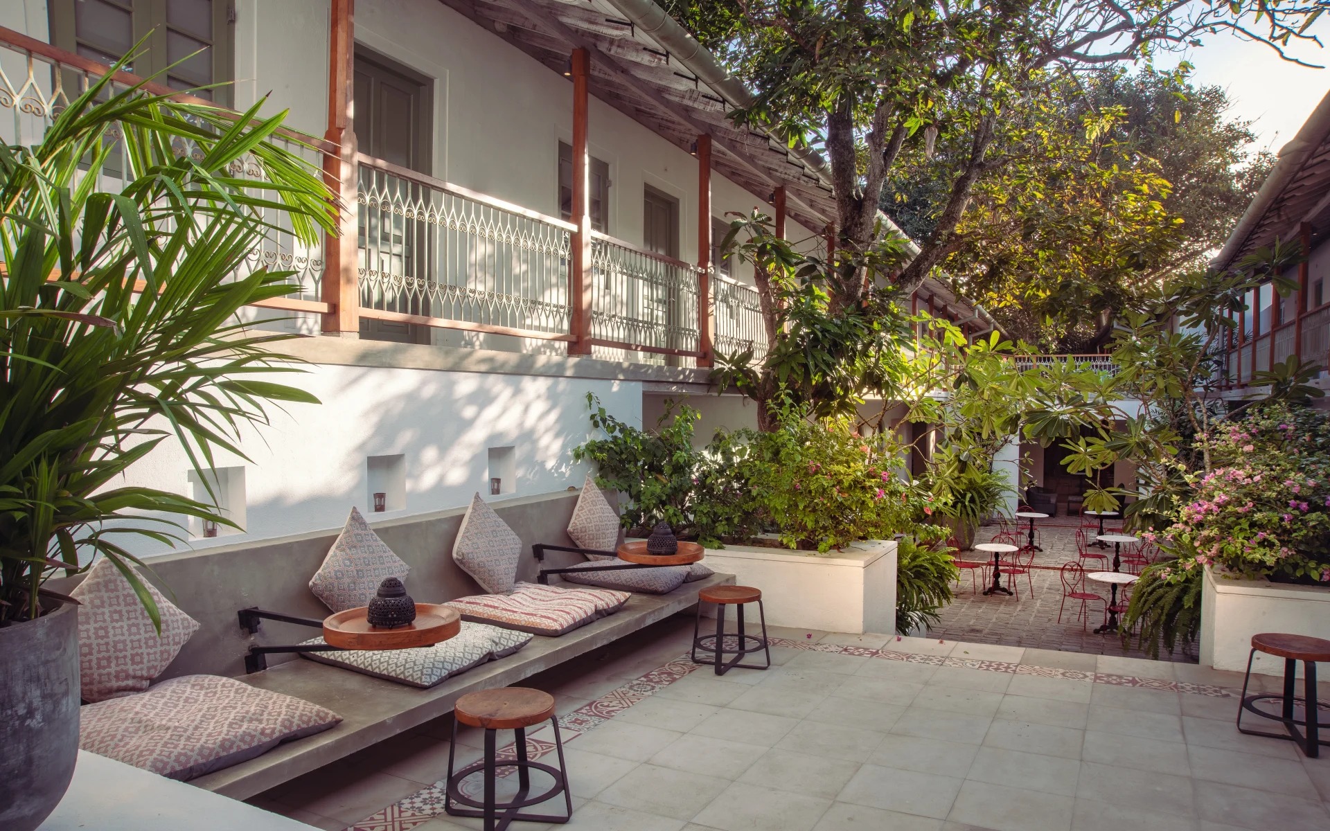 An outdoor seating area is draped in comfy pillows, beside the outdoor courtyard.