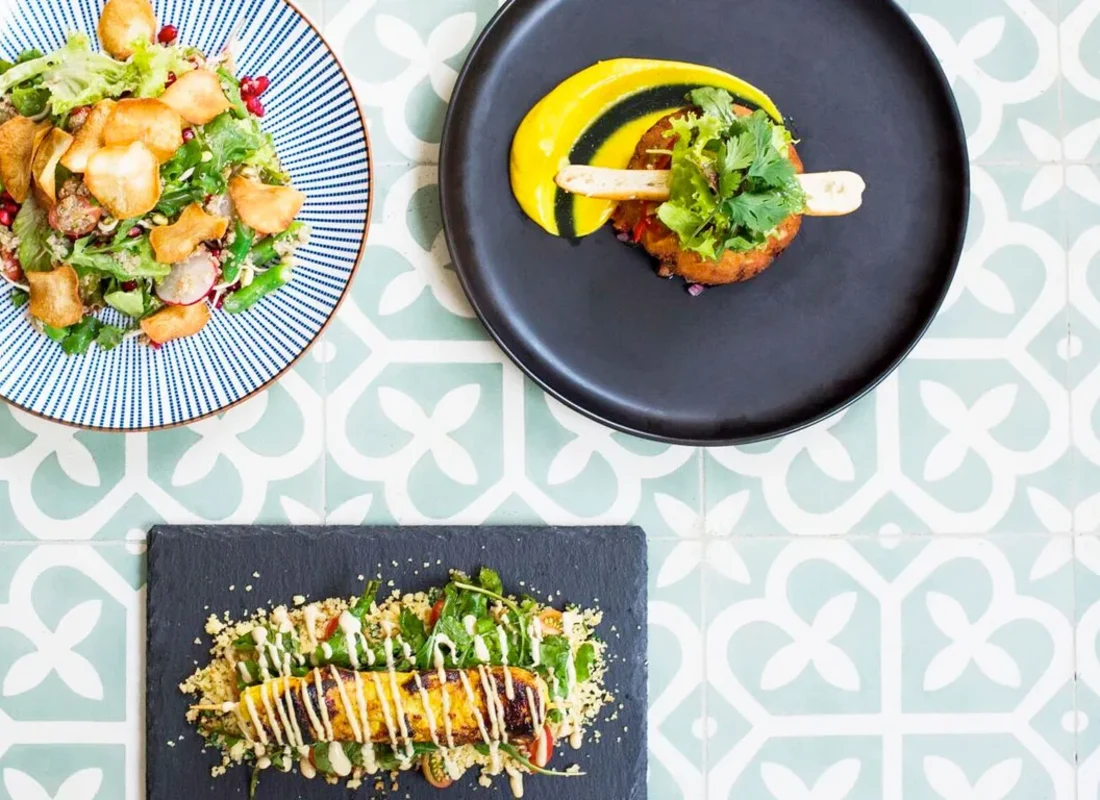 Three colourful dishes are served on slate slabs and plates, presented in a fine-dining style