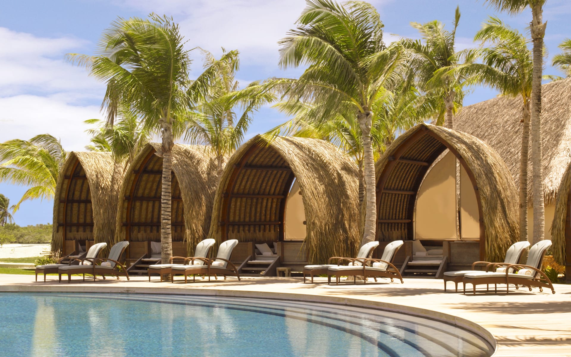 Gorgeous traditional cabanas by a swimming pool 