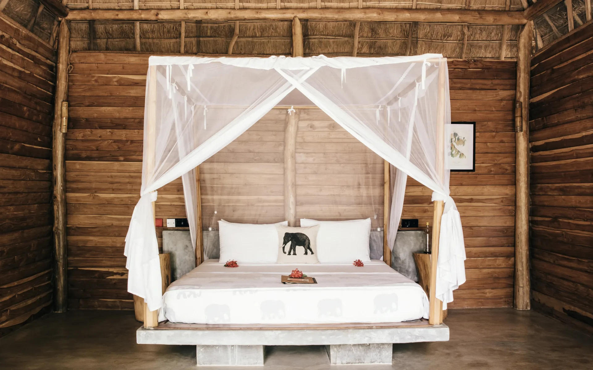 A four-poster bed sits in the centre of one of the bedrooms, dressed in crisp white sheets and a pillow printed with an image of an Asian elephant.