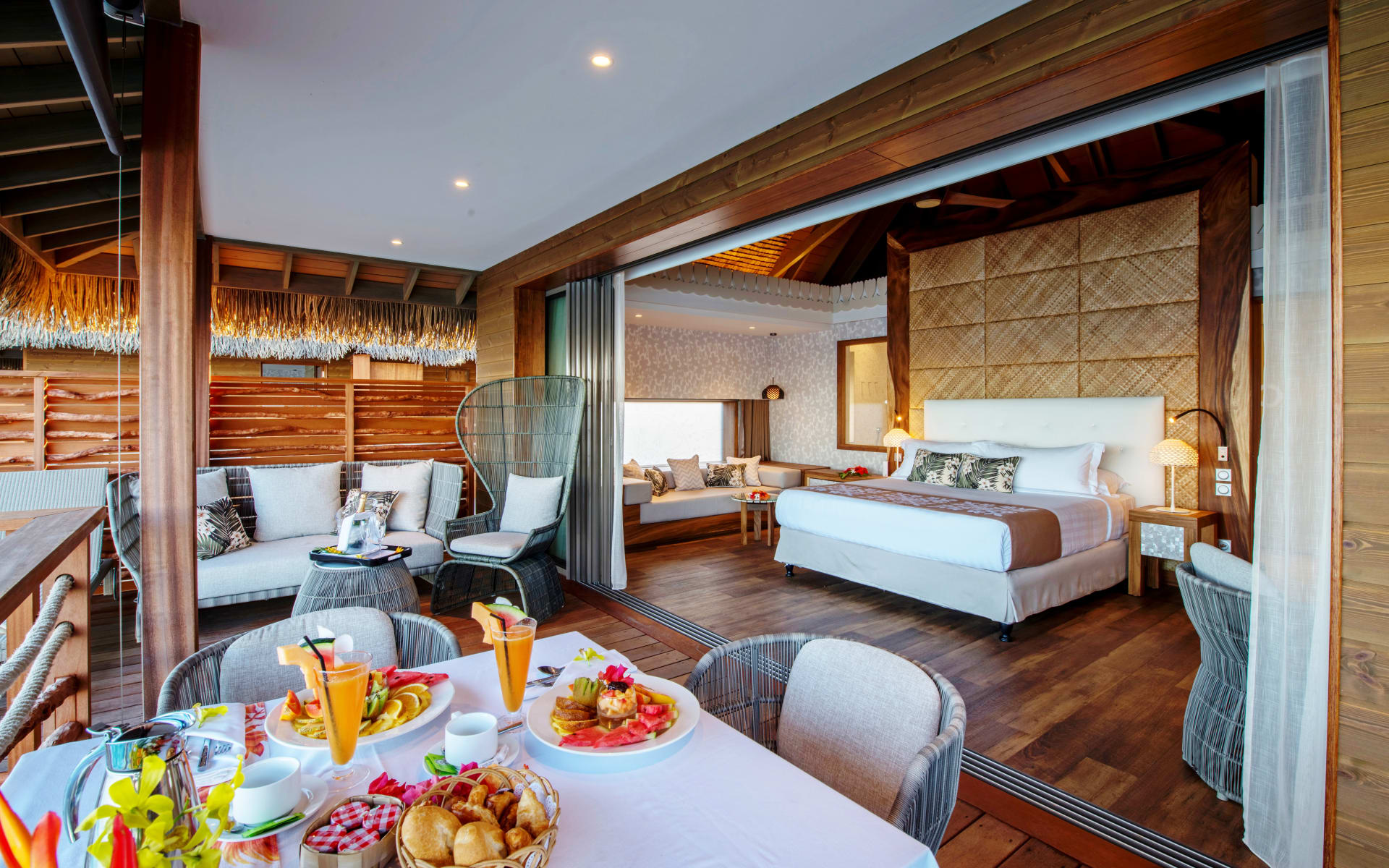 The overwater villa suite has breakfast laid out on the table.