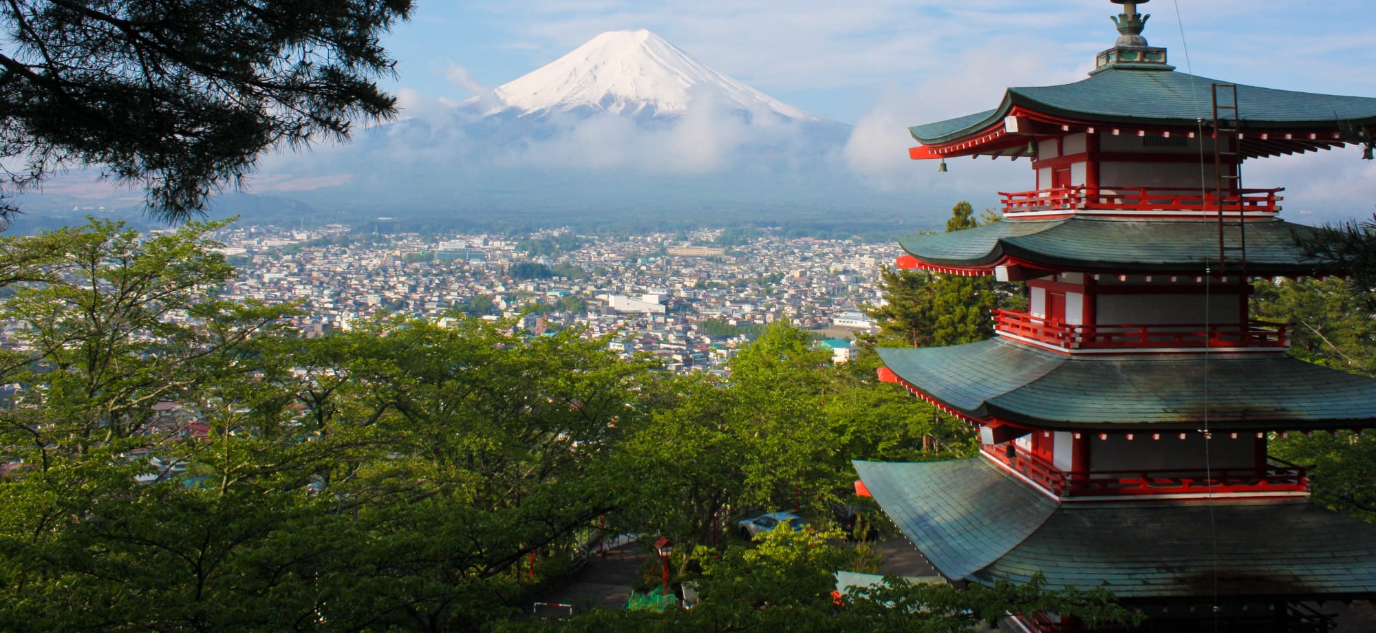 A pagoda overlooks a city and a snow-covered mountain. 