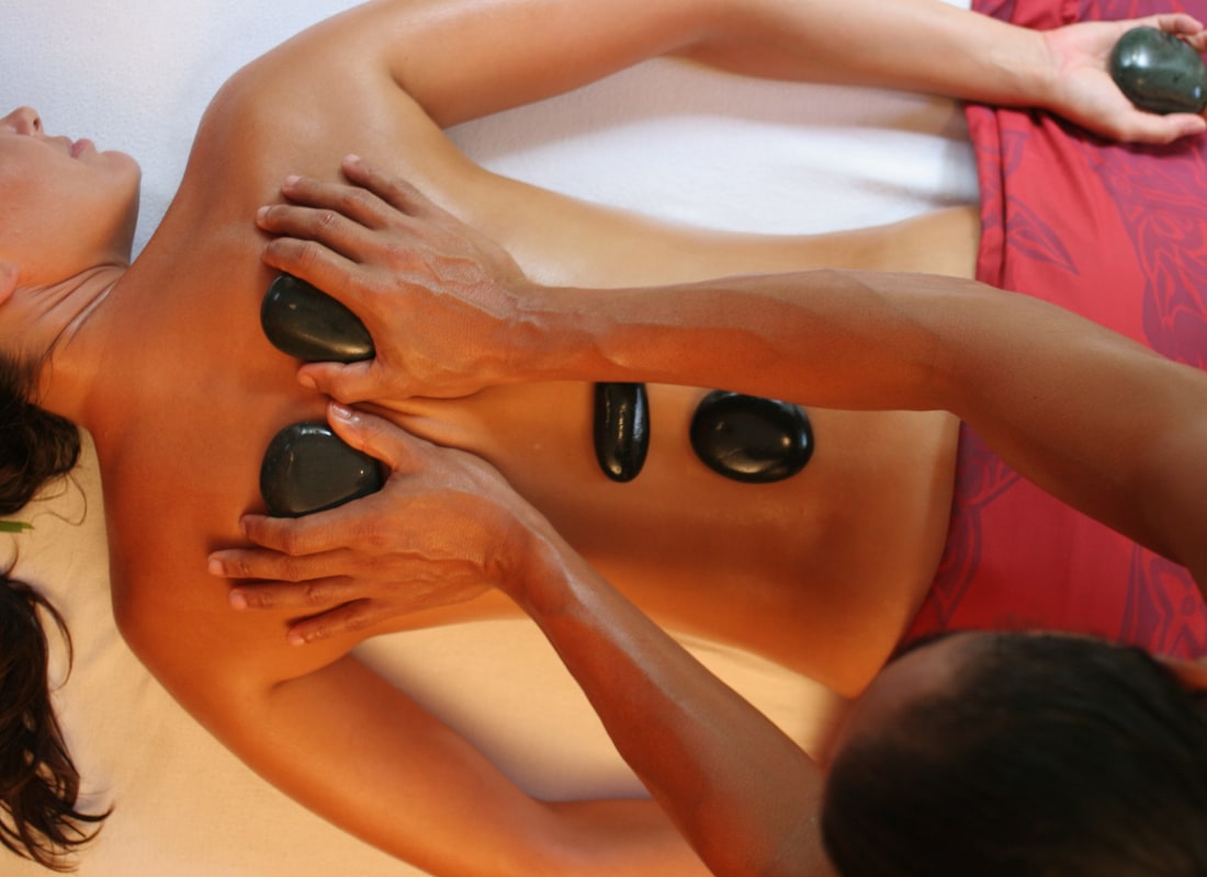 A woman is lying on a table having a massage with hot stones. 