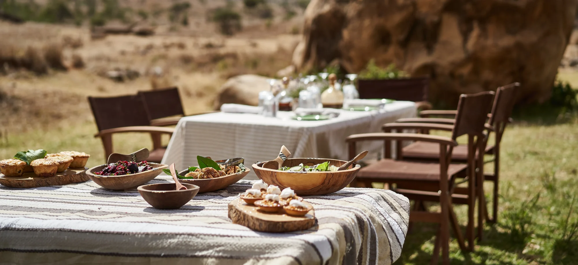 An outdoor dining spread is prepared in the midst of the Borana Conservancy during a sunny day.