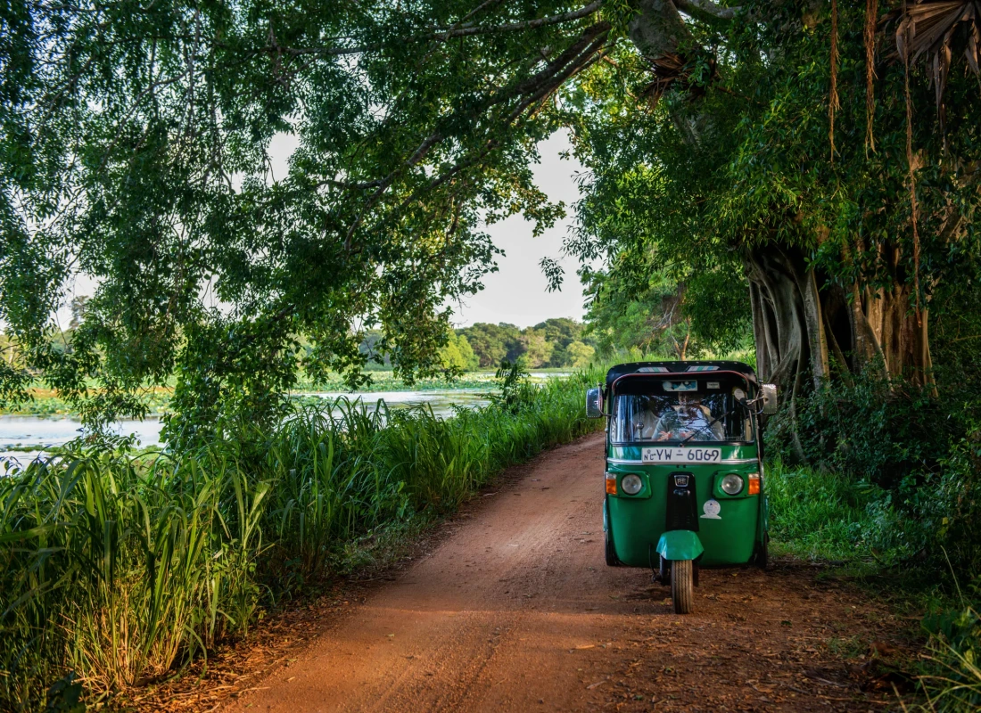 A green tuk-tuk travels along a dusty path near the resort.