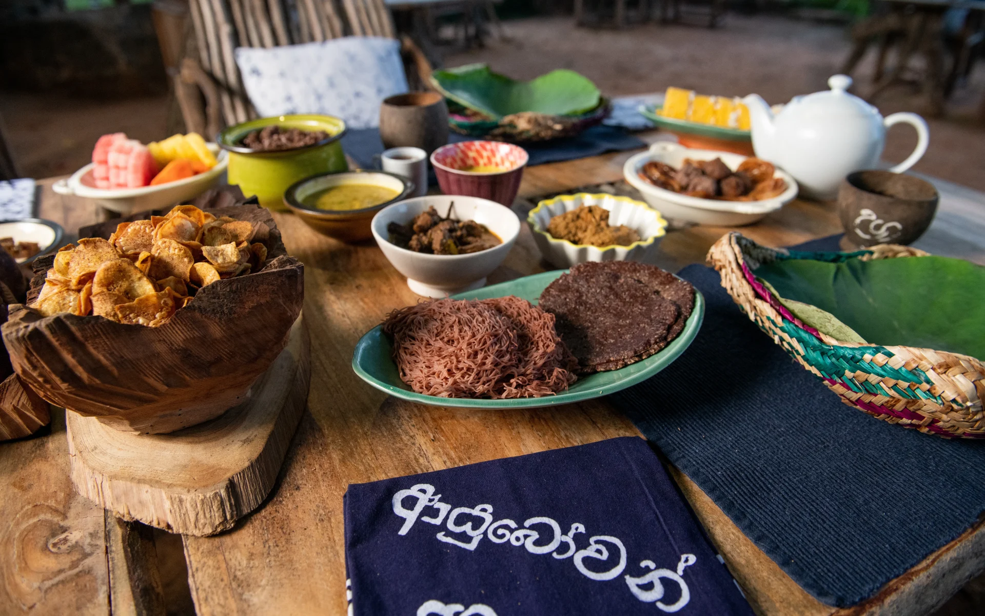 A range of traditional Sri Lankan dishes are laid out on a wooden table.