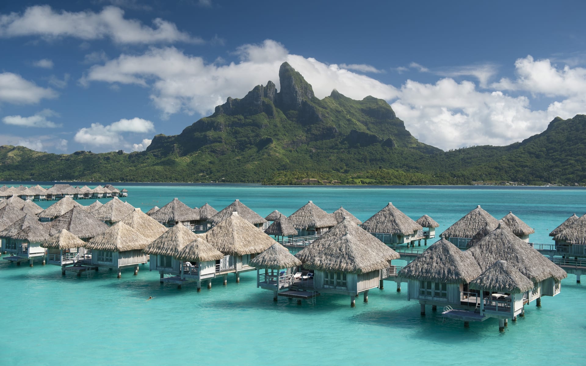 Overwater bungalows with dramatic mountain in the background