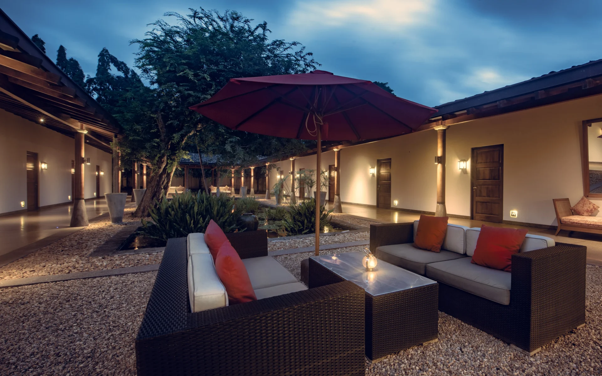 The communal outdoor area at the hotel is set in a pebbled courtyard. Two large outdoor sofas are placed either side of a coffee table.