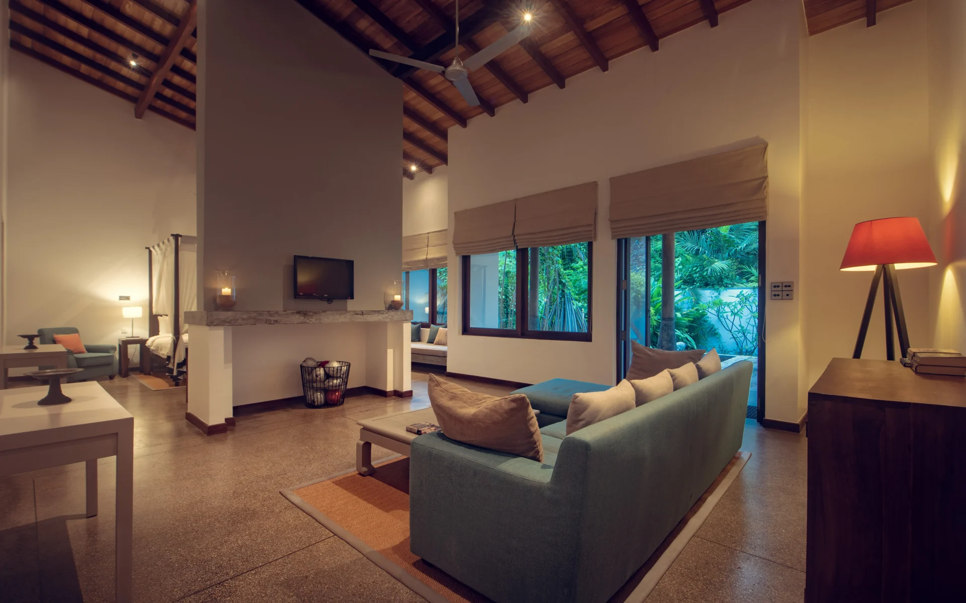 An open living space is equipped with a large, plush sofa and dressed in sleek tiled flooring. Sliding doors open up onto the villa's private veranda