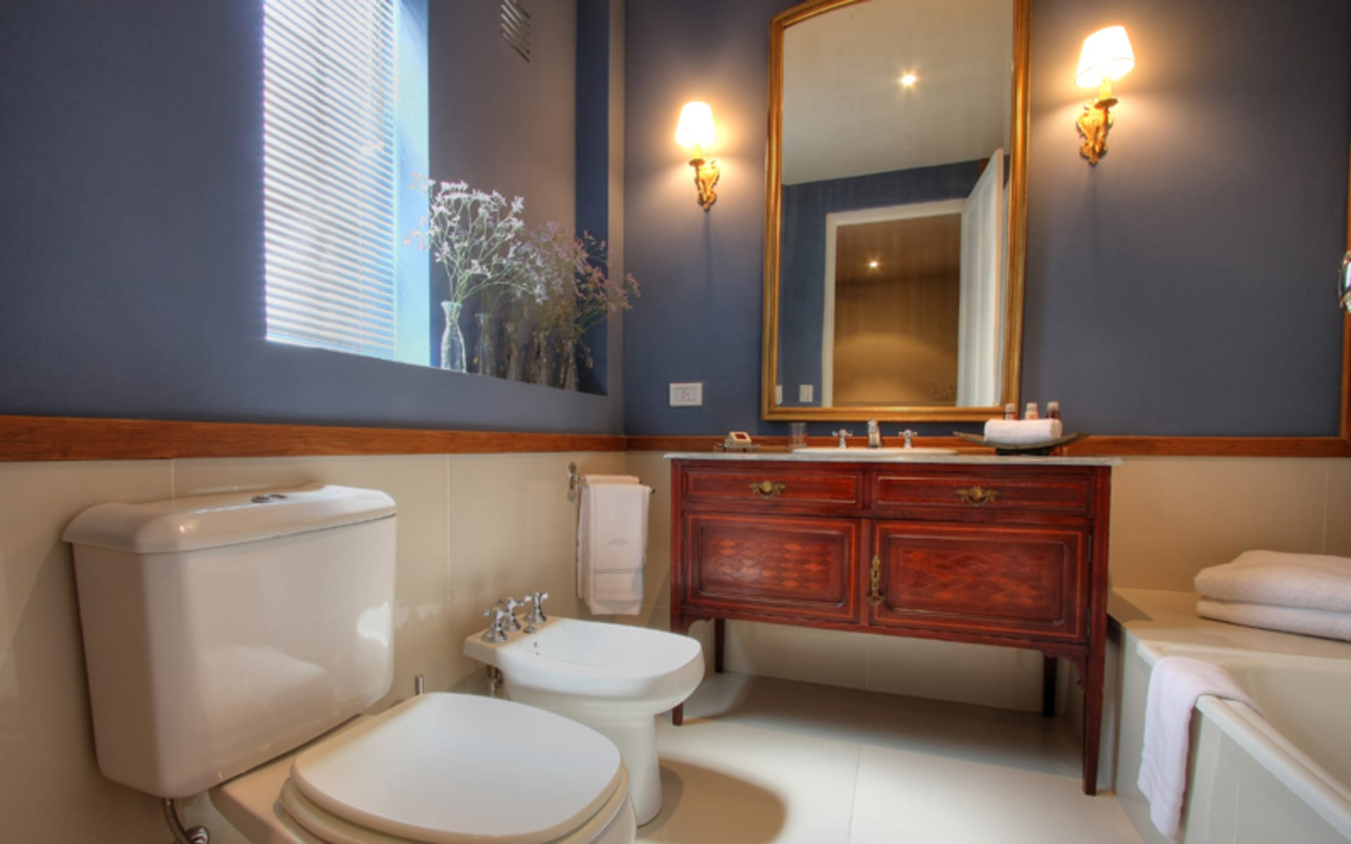 The bathroom has a wooden chest of drawers with a sink above it, a bathtub and a toilet. 