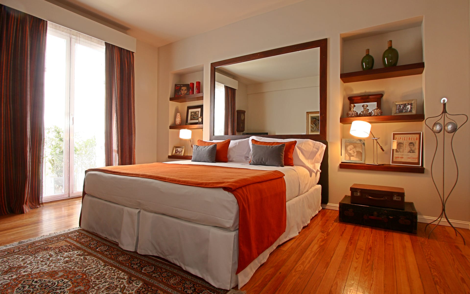 The bedrooms at Legado Mitico are airy, with wooden floors, lots of natural sunlight, a doubled bed with an orange blanket and wooden shelves.