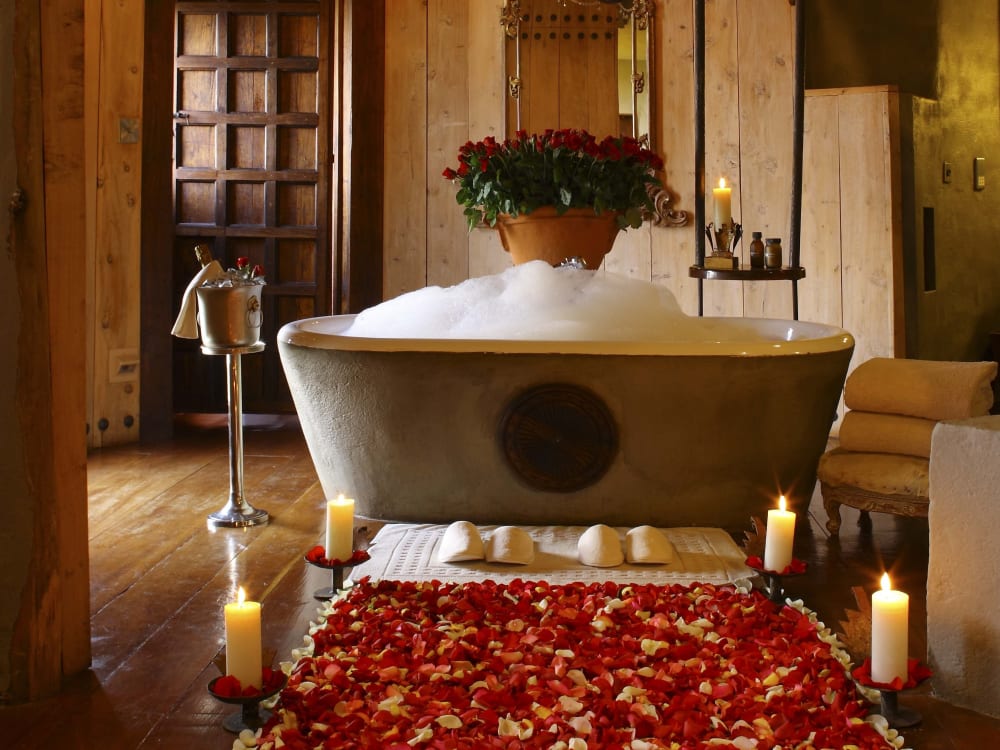 A rolltop bath with bath bubbles, champagne bottle and candles