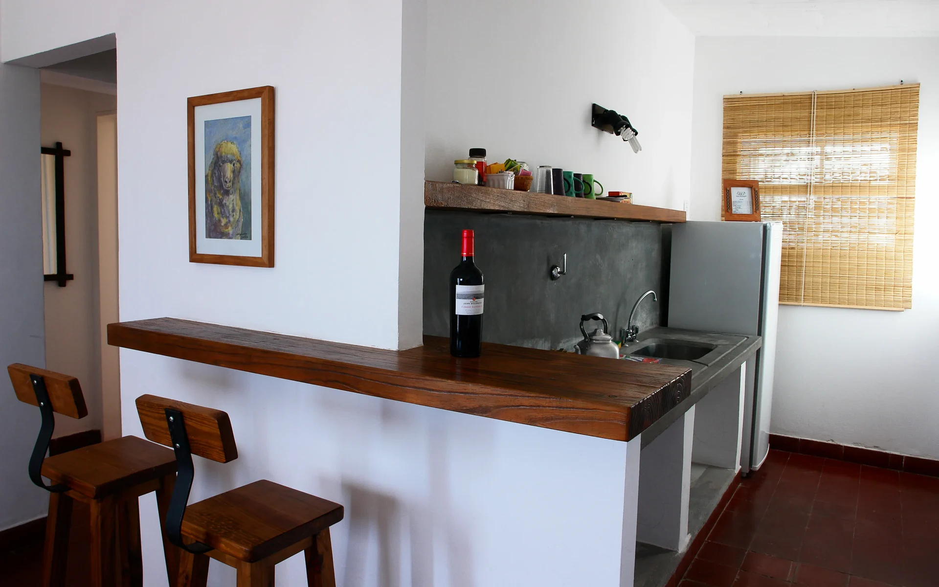 A Kitchenette in one of the Superior Sea Cabins has a traditional and stripped-back style. A bottle of red wine sits on the counter.