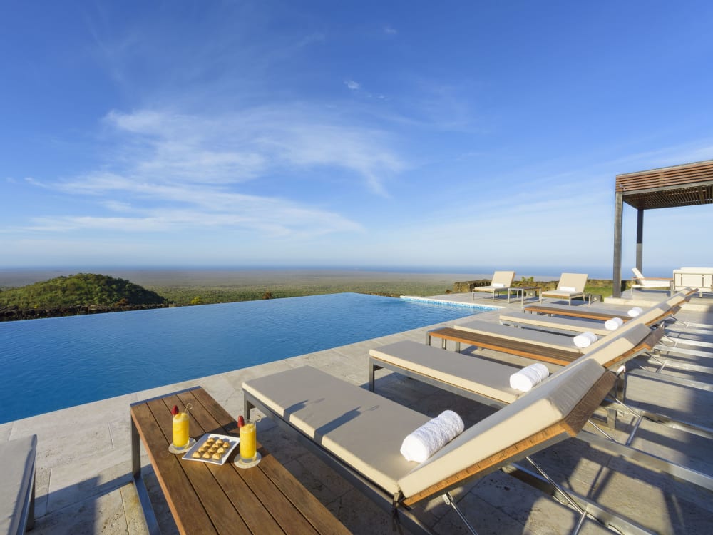 Sun loungers with drinks overlooking an infinity pool