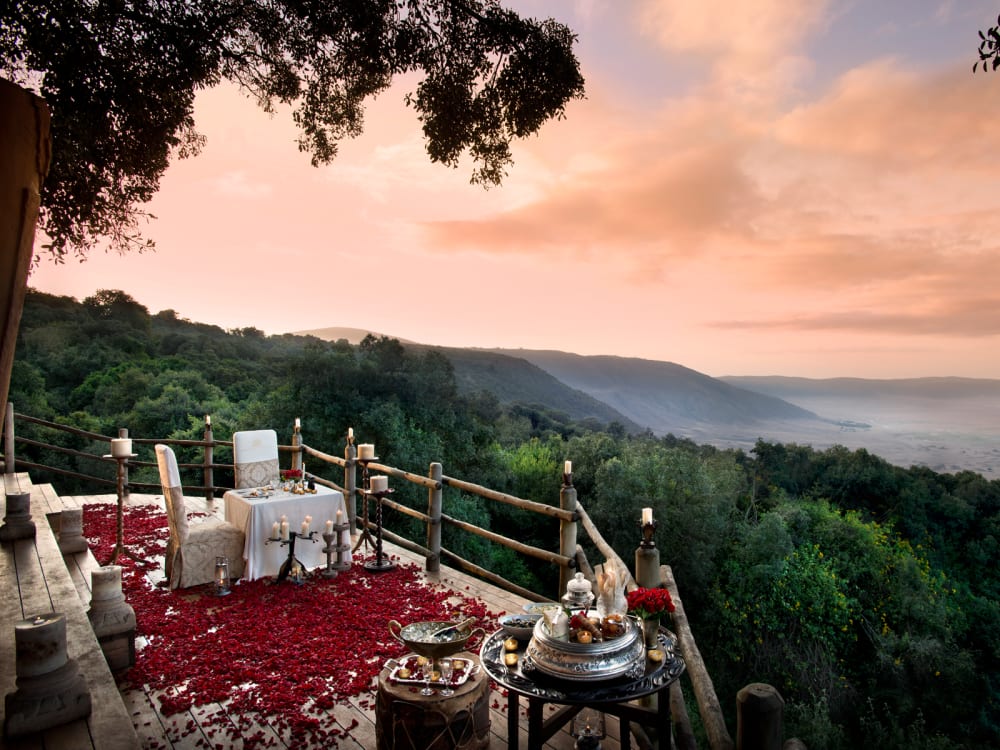 A romantic dining table set up for two on a balcony overlooking the mountains