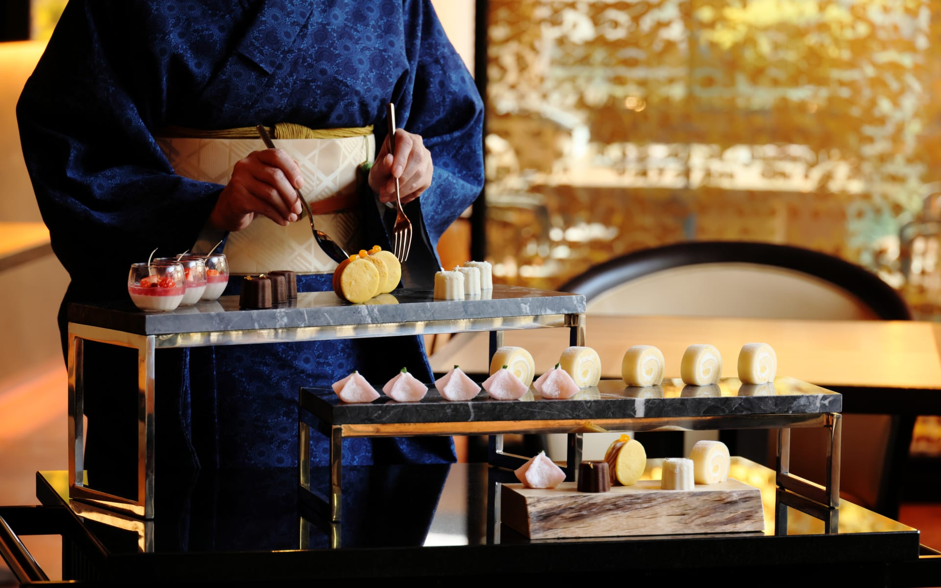 A server in traditional Japanese dress is serving desserts. 