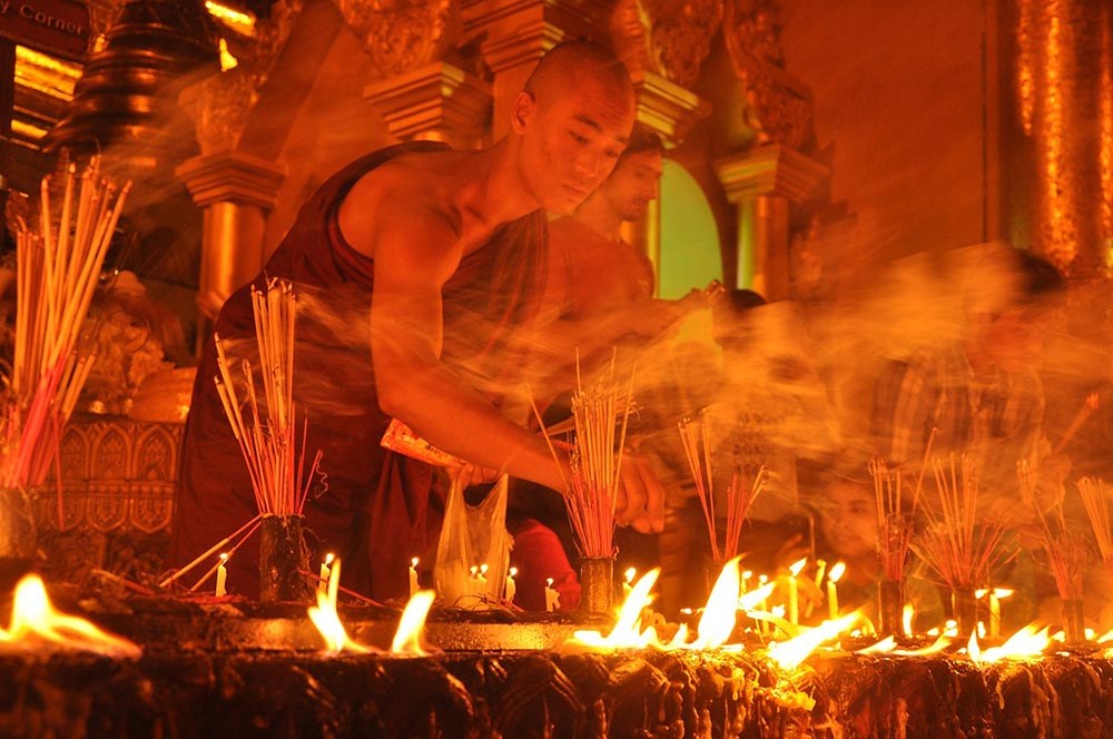 monk lighting a candle for cultural festival in myanmar