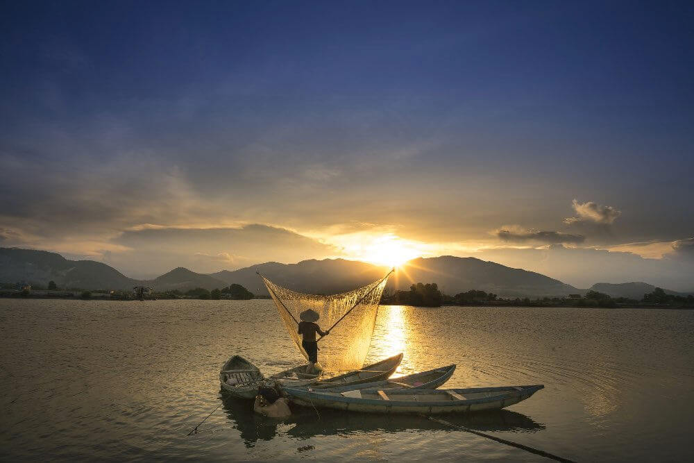 A fisherman casts his net at sunset in southeast Asia
