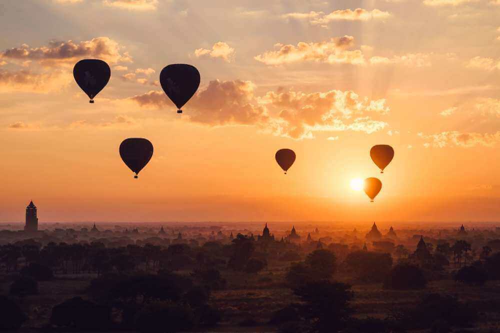 hot air balloons floating over ancient temples at sunrise in bagan myanmar
