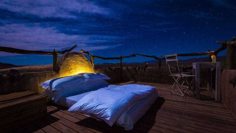 star bed under the night sky at Little Kulala, Sossusvlei, Namibia