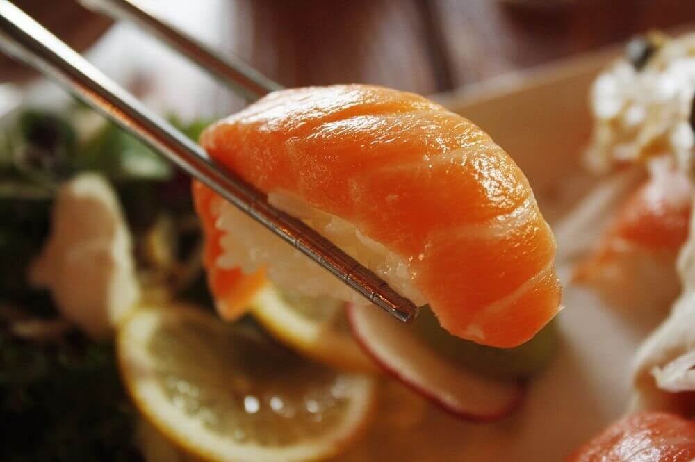 salmon-sushi-held-between-chopsticks