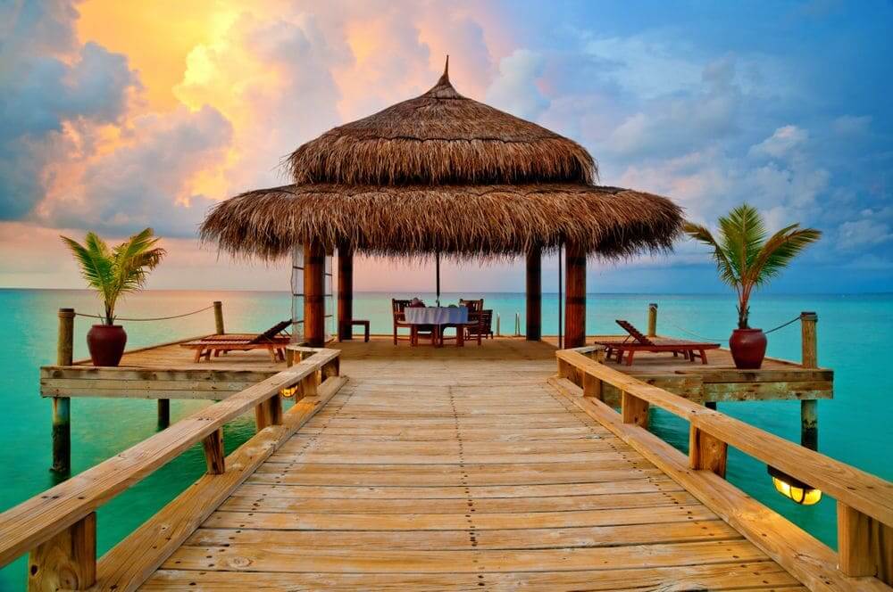 tropical hut over the water at sunset in the maldives