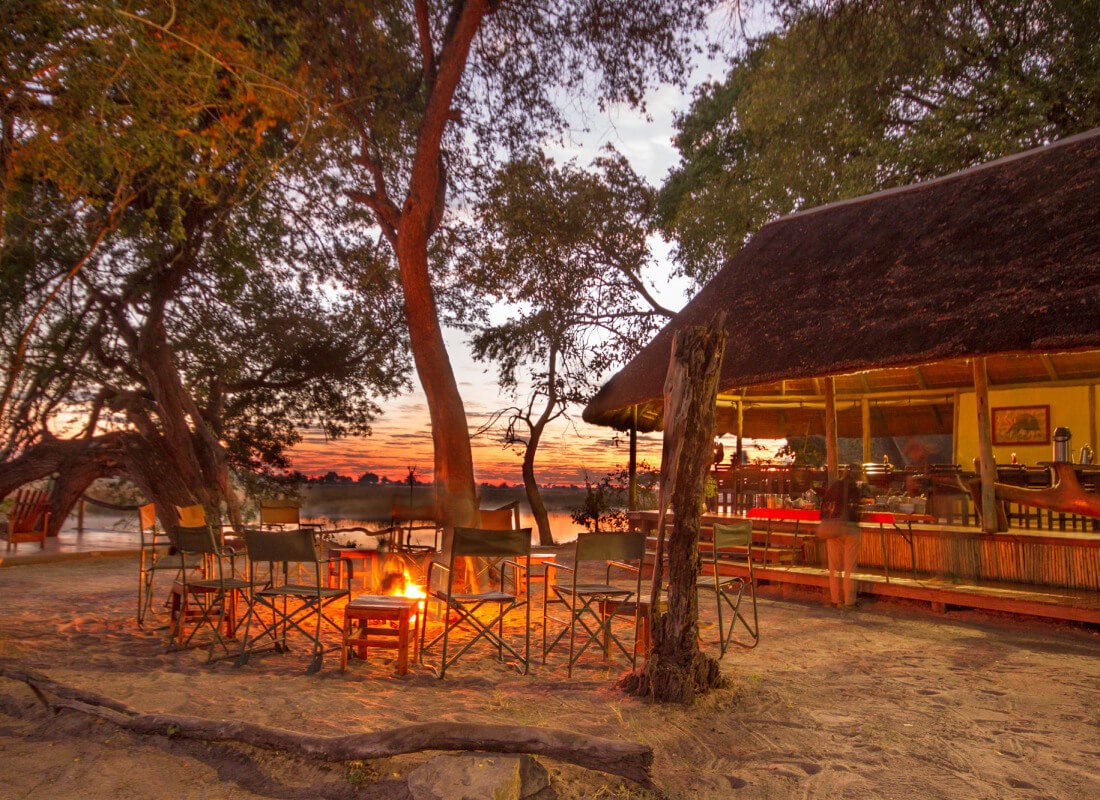 Kwando Lagoon Camp's dining area overlooks a firepit with camp chairs in a circle.