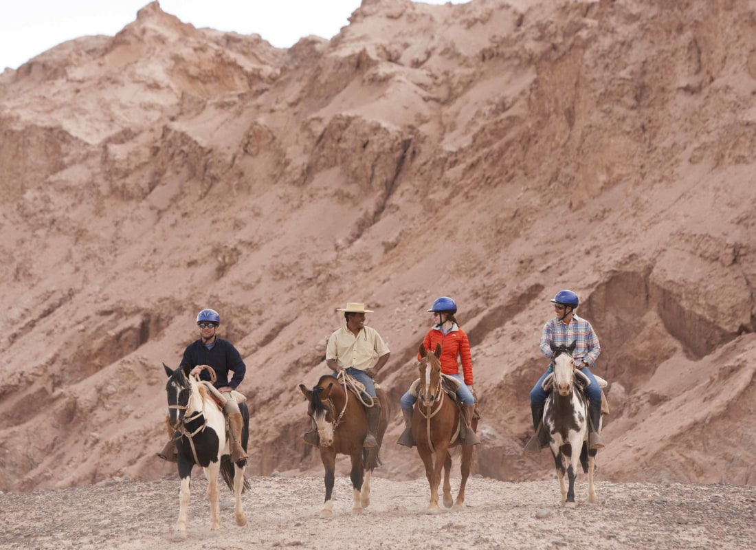 A group of four are horseriding in the desert. 