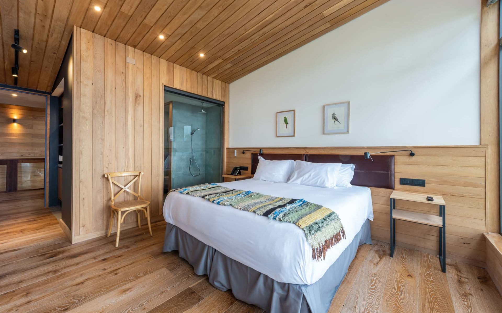 A wood-styled bedroom has a large bed with a lot of open space. 