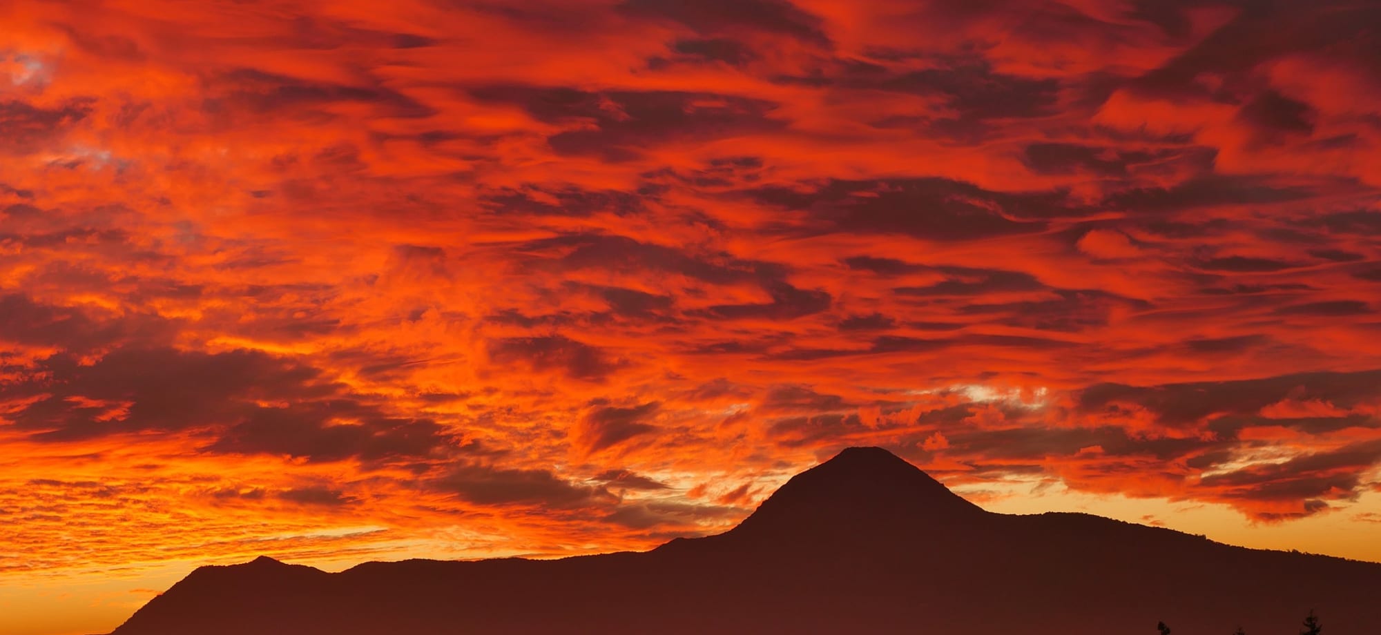 The mountains behind Santiago city are red from the vibrant sunset. 